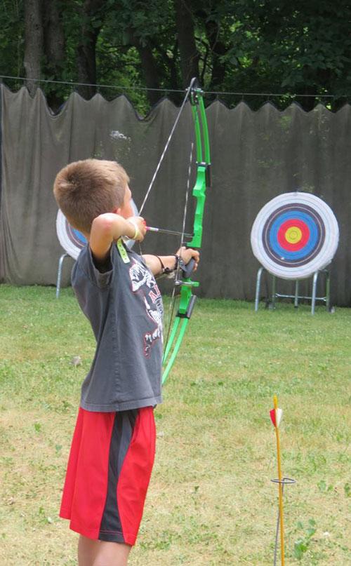 Boy with archery bow aiming at target