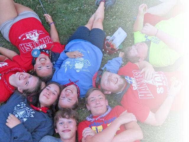 Camp group laying on the ground in a circle - heads together